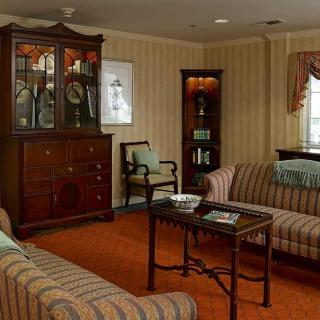 A traditional living room featuring striped sofas, a wooden cabinet, and classic interior decor.