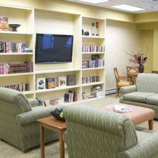 A cozy living room with sofas, armchairs, and built-in bookshelves surrounding a television.