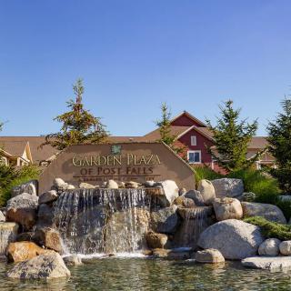 A beautiful resort entrance featuring a waterfall cascading over rocks into a pond, surrounded by trees and a scenic landscape.