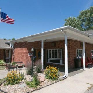 A brick building with an American flag flying, featuring a landscaped entrance.