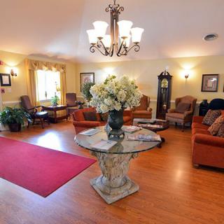 A cozy living room with elegant furniture, a central floral arrangement, and a charming chandelier.