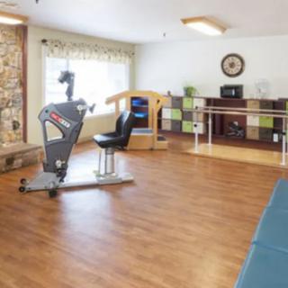 A well-lit fitness room with an exercise bike and other gym equipment for rehabilitation purposes.