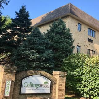A brick apartment building with a sign in front, surrounded by trees.
