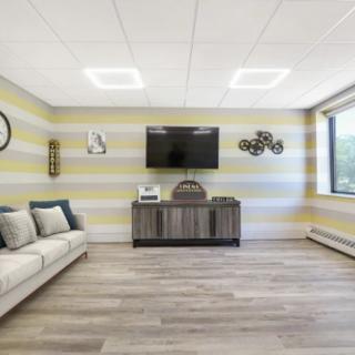 A modern living room with a striped wall, featuring a TV and cozy seating.