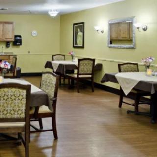 A neatly arranged dining area with several tables and chairs, adorned with subtle decor and lighting.