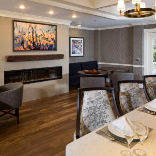 A modern dining room with elegant dcor, featuring a fireplace, artwork on the walls, and a beautifully set table.