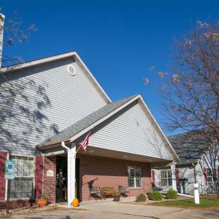 A suburban house with a gabled roof under a clear blue sky, surrounded by trees with autumn leaves.