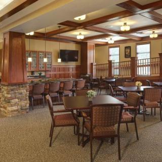A cozy dining area with neatly arranged tables and chairs, featuring warm lighting and classic interior design.