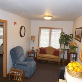 A cozy living room with an armchair, couch, and various decorative items.