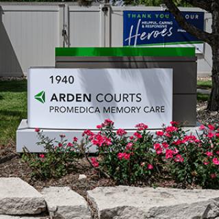 Sign for Arden Courts ProMedica Memory Care surrounded by flowers.