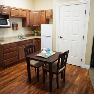 A cozy kitchen with wooden cabinets, a small dining table with two chairs, and modern appliances.