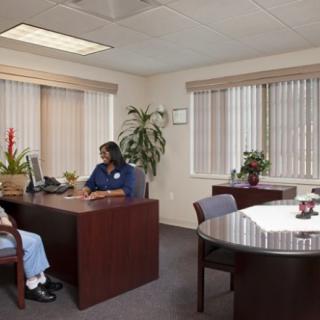 A professional office setting with two people having a discussion at a desk.