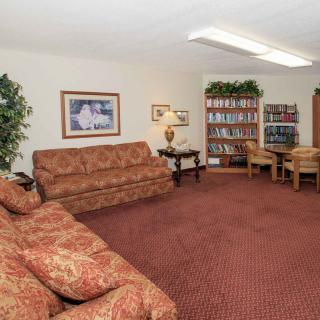 A cozy living room with sofas, a bookshelf, and a table with chairs.