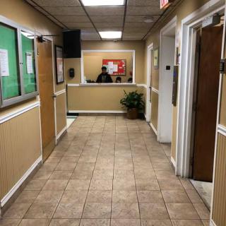 A view down a tiled hallway leading to a reception desk in an office setting.