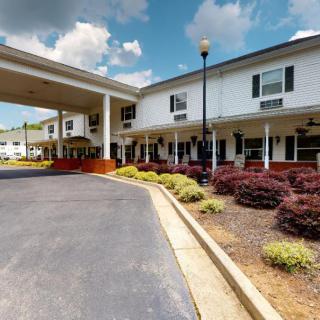 A hotel exterior with a covered entrance and landscaped surroundings under a partly cloudy sky.
