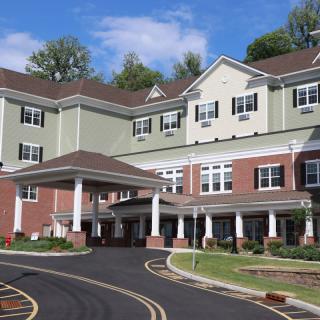A multi-story residential building with a landscaped driveway.