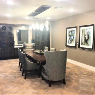 A modern dining room featuring a large table with upholstered chairs, decorative artwork on the walls, and stylish lighting fixtures.