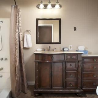 A bathroom featuring a wooden vanity with a mirror and sink, adjacent to a shower curtain.
