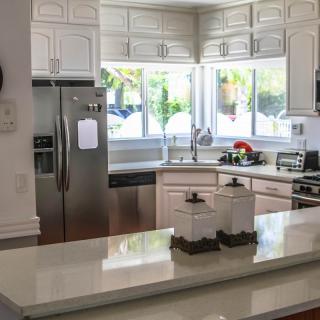 A modern kitchen with white cabinets, stainless steel appliances, and a large window letting in natural light.