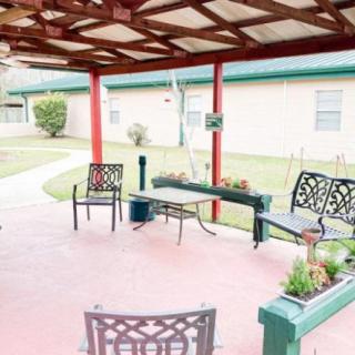 A cozy outdoor patio with chairs and plant boxes under a covered porch.