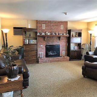A cozy living room featuring a brick fireplace, comfortable seating, and warm lighting.