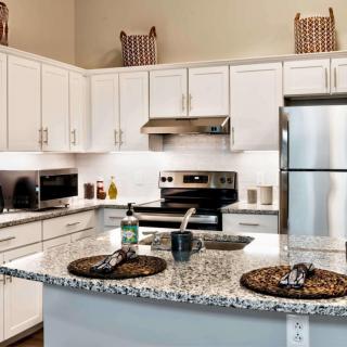 A modern kitchen with white cabinets and stainless steel appliances, featuring a granite countertop.