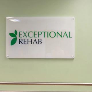 A sign on a green wall that reads 'Exceptional Rehab' indicating a rehabilitation facility.