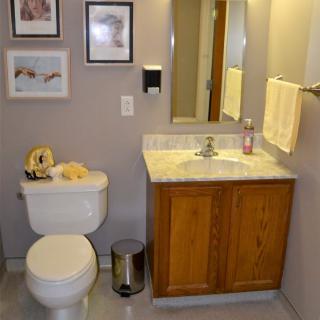 A neatly organized bathroom with a sink, toilet, and mirror, adorned with wall decor and a towel.