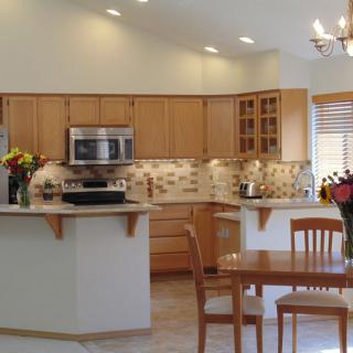 A modern kitchen with wood cabinets and a dining area.