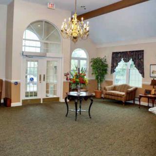 A spacious and elegantly decorated lobby with a chandelier, seating area, and large windows.