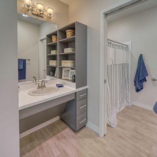 A modern bathroom with a sink, mirror, and open shelving.