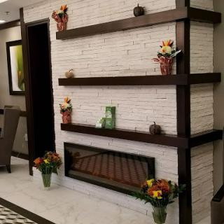 A stylish interior featuring a decorative wall with shelves and a cozy fireplace, complemented by floral arrangements.