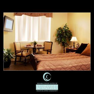 A cozy hotel room interior featuring a bed, chairs, television, and window with natural lighting.