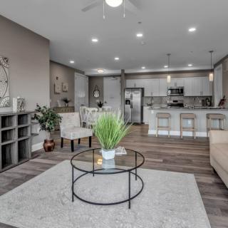 A modern open-floor-plan living room and kitchen with minimalist decor and neutral tones.