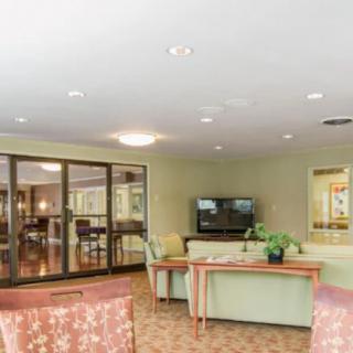 A spacious lobby with comfortable seating, a television, and decorative plants.