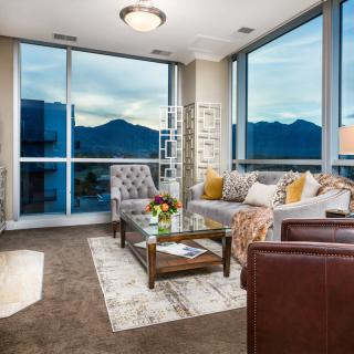 A modern living room with large windows overlooking a mountain view, featuring stylish furniture and cozy decor.