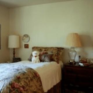 A cozy bedroom with a neatly made bed, lamps on both sides, and decorative pillows.