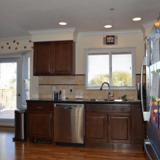 A modern kitchen with dark wood cabinets, stainless steel appliances, and a large window.