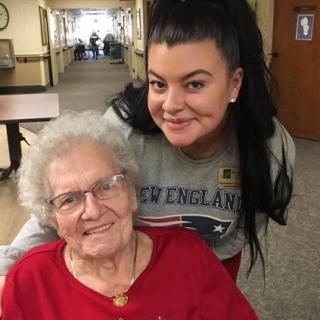A joyful moment shared between a young woman and an elderly lady in a cozy indoor setting.