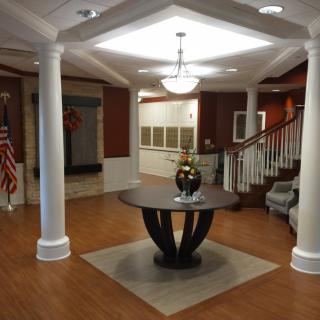 A well-decorated lobby with a central table, stairs, and chandelier.