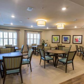 A well-lit dining area with multiple tables and chairs, featuring framed artwork on the walls.