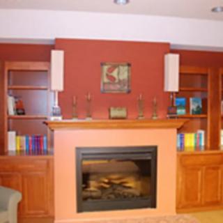 A cozy living room with a central fireplace surrounded by wooden shelves and decorative items.