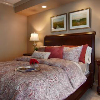 A beautifully decorated bedroom featuring a comfortable bed with patterned bedding, accent pillows, and decorative artwork on the walls.