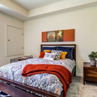 A cozy bedroom with vibrant bedding, decorative cushions, and wall art.