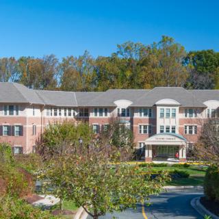 A large residential building surrounded by greenery and trees under a clear blue sky.