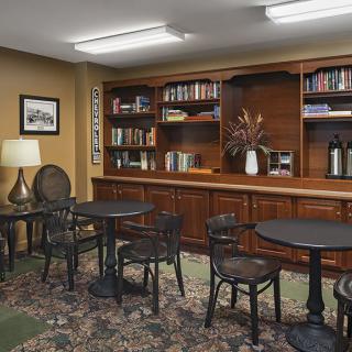 A cozy library room with bookshelves, tables, and chairs.