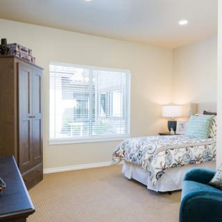A cozy bedroom with a large bed, wardrobe, and a window providing natural light.