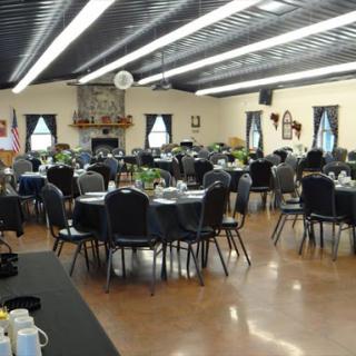 A spacious banquet hall arranged for dining, featuring round tables and elegant decor.