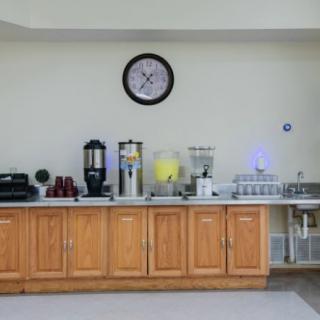 A kitchen counter with a coffee and beverage station, complete with a clock on the wall above.