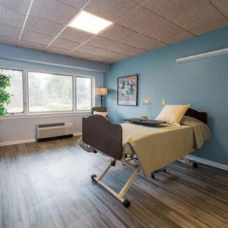 A clean and well-lit hospital room featuring a single bed and large window.